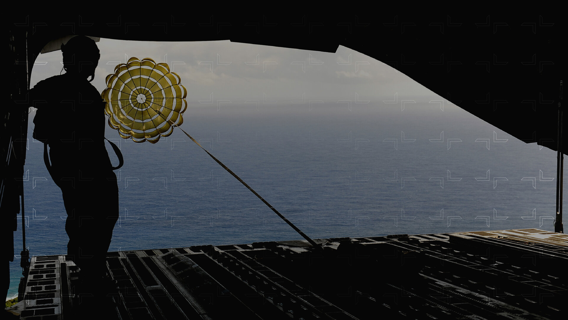 person in back of open plane with parachuted box