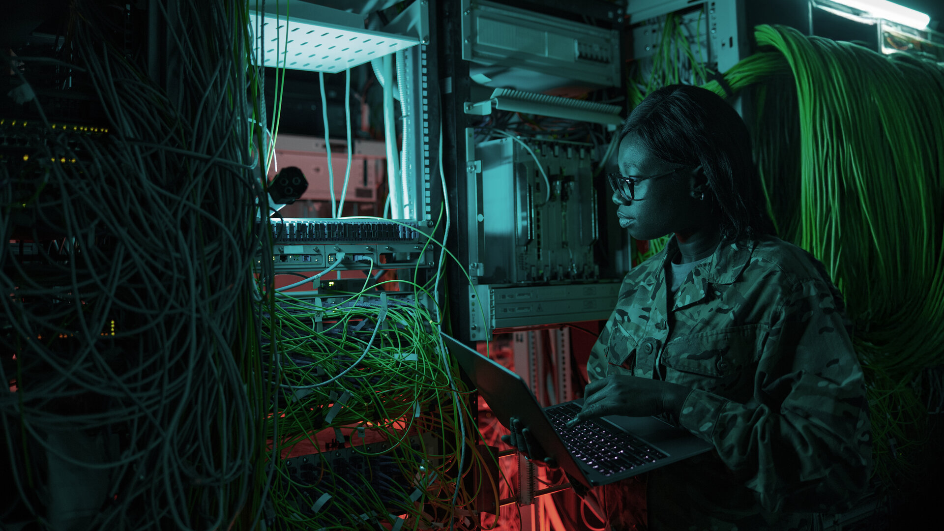 person in military fatigues working in a server room